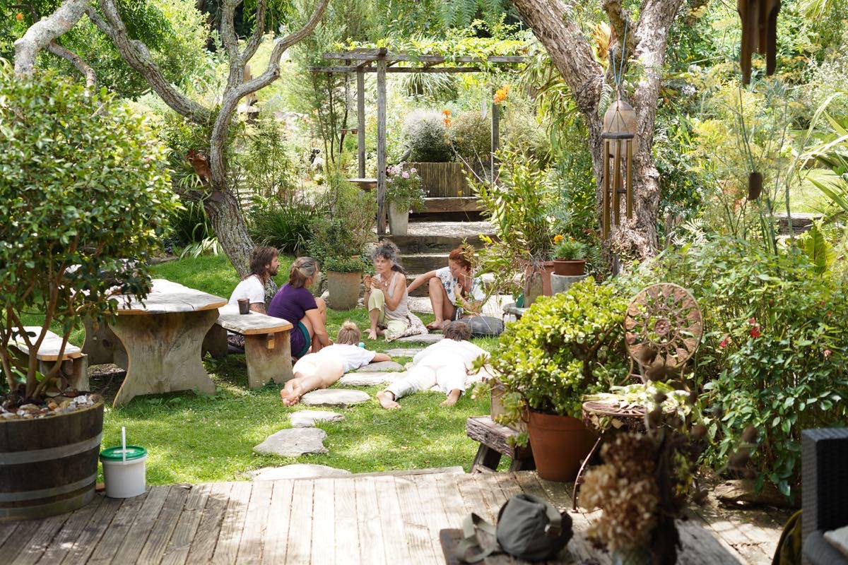A group of people sitting and talking together in a lush home garden